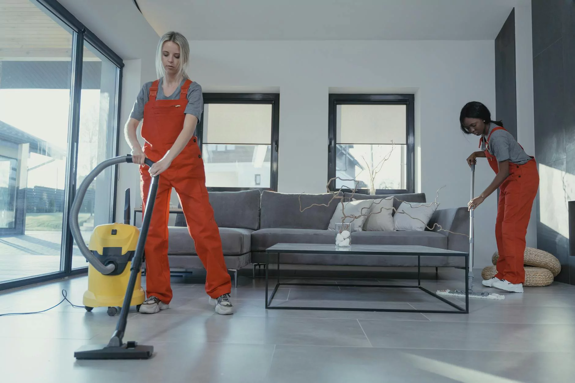 Two people vacuuming and mopping a bright living room